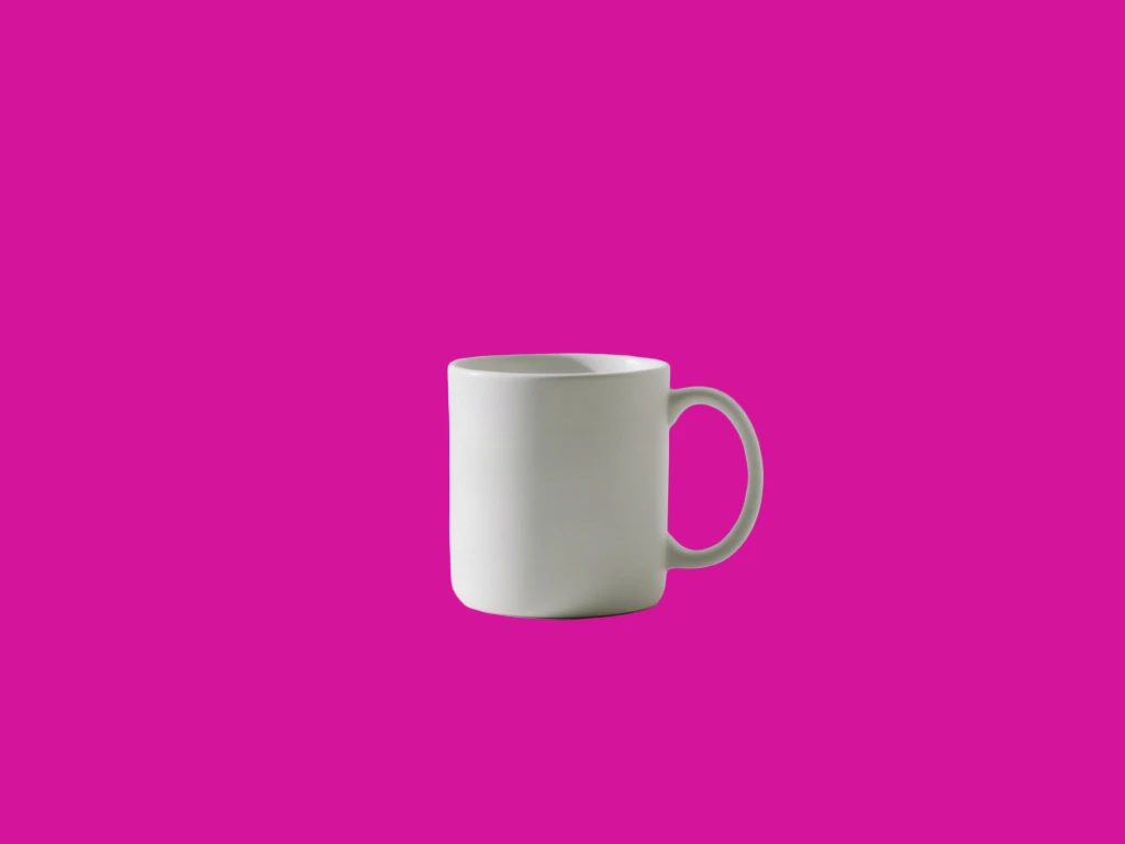 Matte white ceramic mug on a white table against a white wall cut out and placed on a saturated magenta test colour